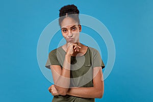 Puzzled pensive young african american woman girl in casual t-shirt posing isolated on bright blue background. People