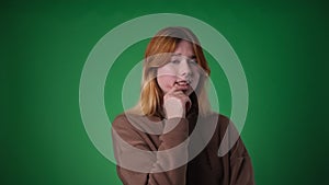 Puzzled Red haired Woman on Green Background