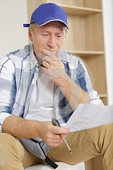 puzzled senior man reading instructions for furniture assembly