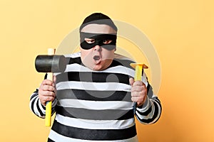 Puzzled surprised burgler in mask holding tool for crime photo