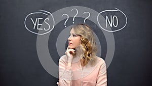 Puzzled woman choosing between yes no, stereotype of uncertain female thinking photo