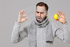 Puzzled young man in gray sweater, scarf isolated on grey background. Healthy lifestyle, ill sick disease treatment