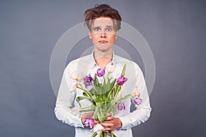 Sad young guy after a bad date, with a spoiled hairdo and a broken bouquet of flowers