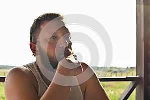 Puzzled young man stroking touching beard. Man with a beard. Portrait. Farmer. Ranch