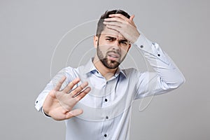 Puzzled young unshaven business man in light shirt posing isolated on grey background. Achievement career wealth