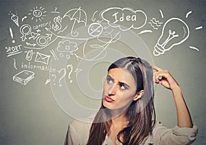 Puzzled young woman thinking scratching head has many ideas looking up