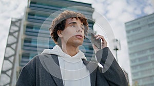 Puzzled youngster calling cellphone at urban settings. Young man waiting friend