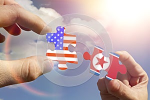 Puzzles in the form of flags of North Korea and the United States of America in the hands