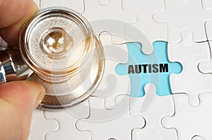 On puzzles a hand with a stethoscope, on a blue background the inscription - AUTISM