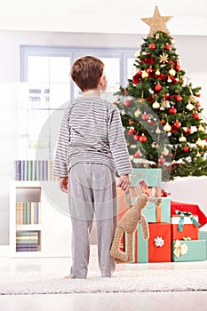 Pyjama boy with toy at christmas tree