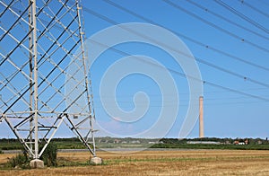 pylon with high voltage cables for transport of electricity and the chimney of thermoelectric power plant