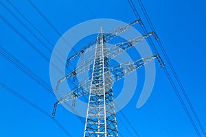 Pylon and high-voltage lines under bright blue sky