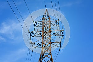 The pylon of the high-voltage power line against the blue sky. Electricity pylon against blue cloudy sky