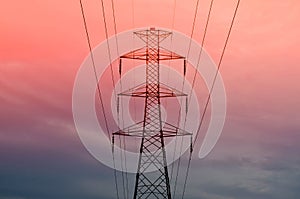 Pylon with power lines against orange sky - twilight