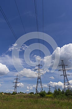 Pylons of high-voltage power transmission lines against a blue sky