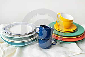 A pyramid of brightly colored bowls, plates and cups of different sizes and colors on the kitchen table. Scandinavian