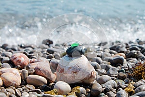 The pyramid is built on a pebble beach of sea pebbles with a matte smooth green glass at the top. Against the background of waves