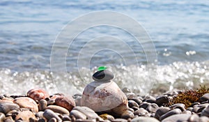 The pyramid is built on a pebble beach of sea pebbles with a matte smooth green glass at the top. Against the background of waves