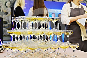 Pyramid of champagne glasses at a party. Champagne pyramid on the background of the guests