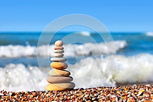 Pyramid of colored pebbles on a background of the summer sea. Co