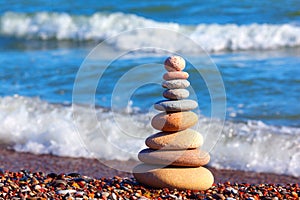 Pyramid of colored pebbles on a background of the summer sea. Concept of harmony, balance and meditation