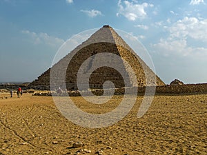 A pyramid at Giza, Egypt protrudes skywards from the sandy desert floor photo