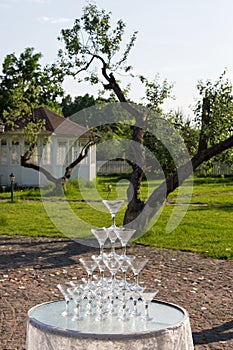 Pyramid of glasses for champagne at outdoor garden in wedding ceremony.