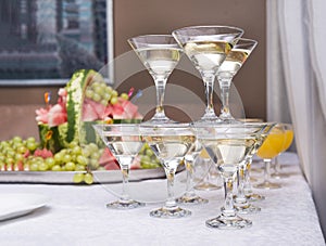 Pyramid of glasses of sparkling wine, fruit in the background