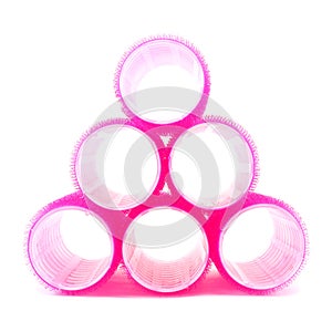 Pyramid made of pink hair curlers on white