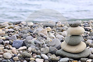 Pyramid of pebbles on the beach.Waves in background balanced zen stones, spa and relax concept, meditation