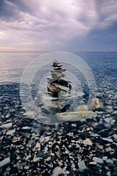 Pyramid of sea stones in calm water near the shore