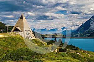 Pyramid shaped church and lake Mont-Cenis among mountains in France