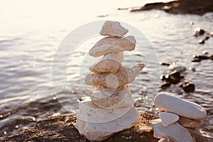 Pyramid of the smaller pebbles on the sea shore. Stones, against the background of the setting sun