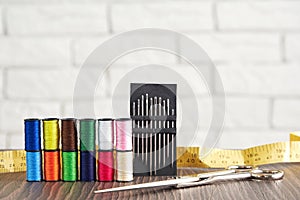 Pyramid of spools of colorful sewing threads and needles, measuring, scissors