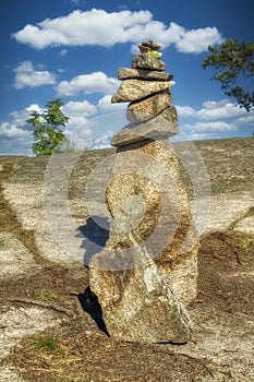 A pyramid of stones on a background of a blue sky with clouds