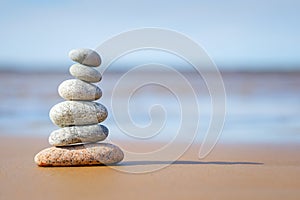 Pyramid stones balance on the sand of the beach. The object is in focus