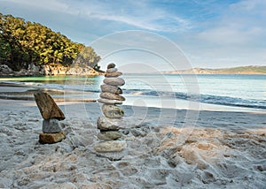 Pyramid stones balance on the sand of the beach. The object is in focus, the background is blurred