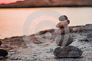 Pyramid stones balance on the sand of the beach. The object is in focus,sunset view.