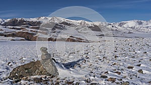 The pyramid of stones is built on a snow-covered high-altitude plateau.