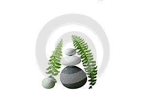Pyramid of stones on a green background and fern leaves. Spa concept, balance and tranquilit.