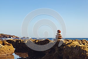 Pyramid of stones for meditation lying on sea coast. Zen stones sunset sea peace of mind concept.