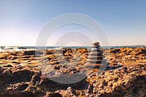 Pyramid of stones for meditation lying on sea coast. Zen stones sunset sea peace of mind concept.