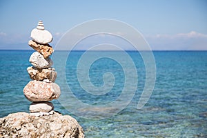 Pyramid of stones at the ocean. Blue water background.