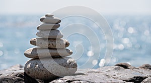 Pyramid stones on the seashore on a sunny day on the blue sea background. Happy holidays. Pebble beach, calm sea, travel