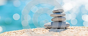 Pyramid stones on the seashore on a sunny day on the blue sea background. Happy holidays. Pebble beach, calm sea, travel