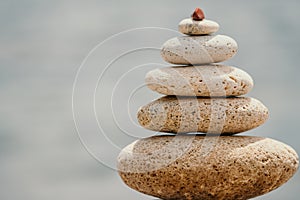 Pyramid stones on seashore with warm sunset on sea background for perfect holiday. Pebble beach and calm sea create a
