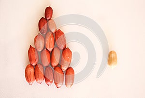 A pyramid of united red peanuts and one different outcast peanut concept isolated on white