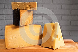 Pyramid of various cheeses on a wooden Board against a brick wall