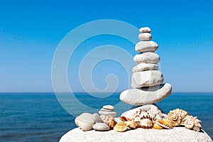 Pyramid of white stones and shells on a background of blue sky and sea