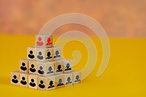 Pyramid of wooden blocks with man and woman icons portrayig a hierarchy, human resources concept